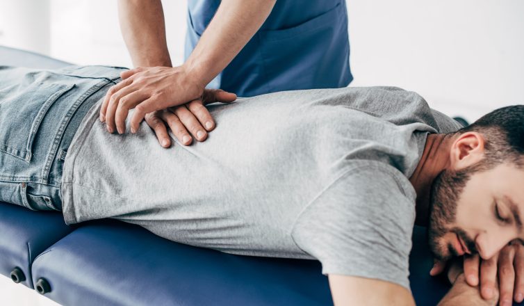 chiropractor massaging back of man on massage table in hospital