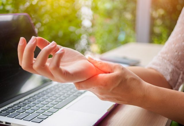 closeup woman holding her painful hand from using computer. office syndrome hand pain by occupational disease.